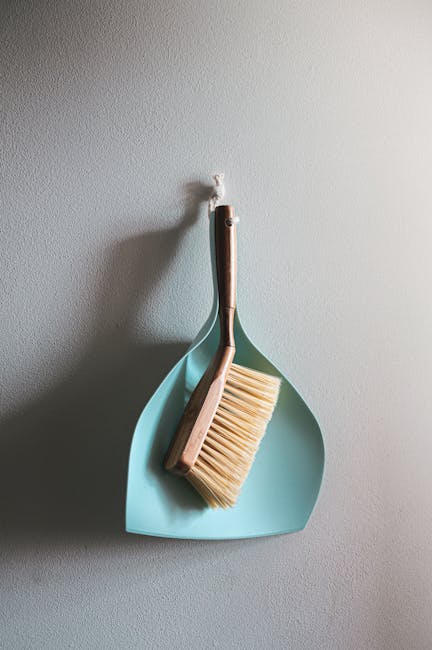 A professional cleaner from Deep Cleaning Belsize Park is performing surface cleaning in a residential bedroom. The cleaner, dressed in black with gloves, is wiping a wooden dining table with a cloth,